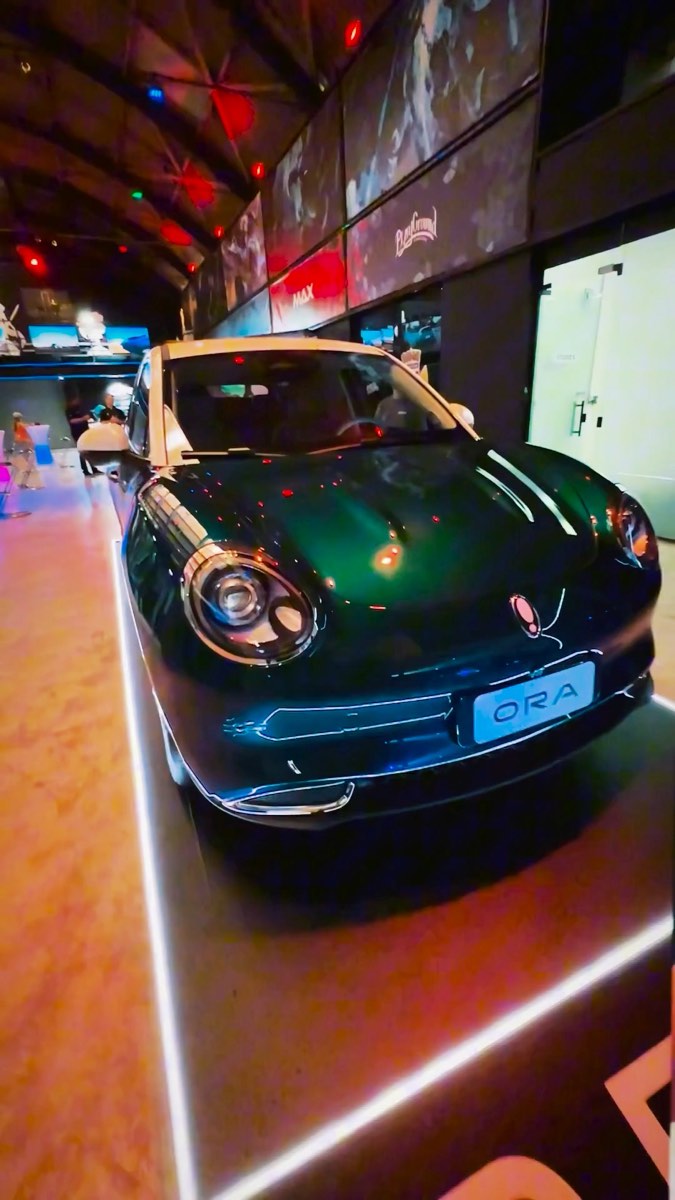 O carro ORA de frente no piso do salão, iluminado