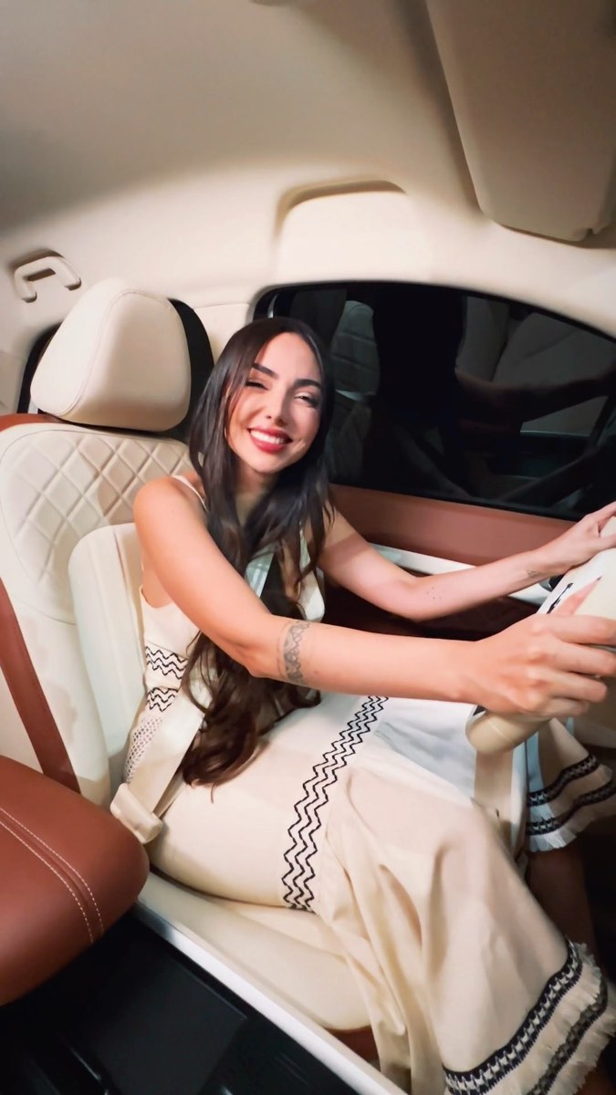 Convidada sentada no banco claro do carro, sorrindo