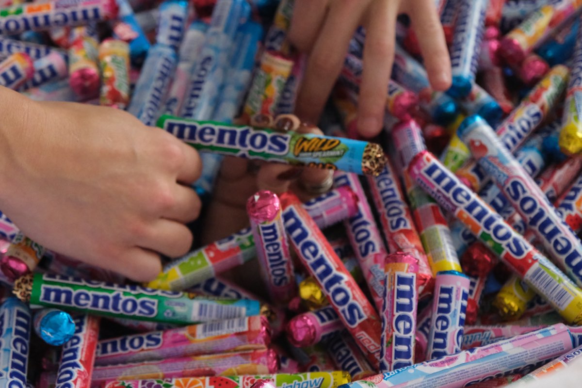 Bastidor: mão mergulhando na pilha de Mentos de todos os sabores