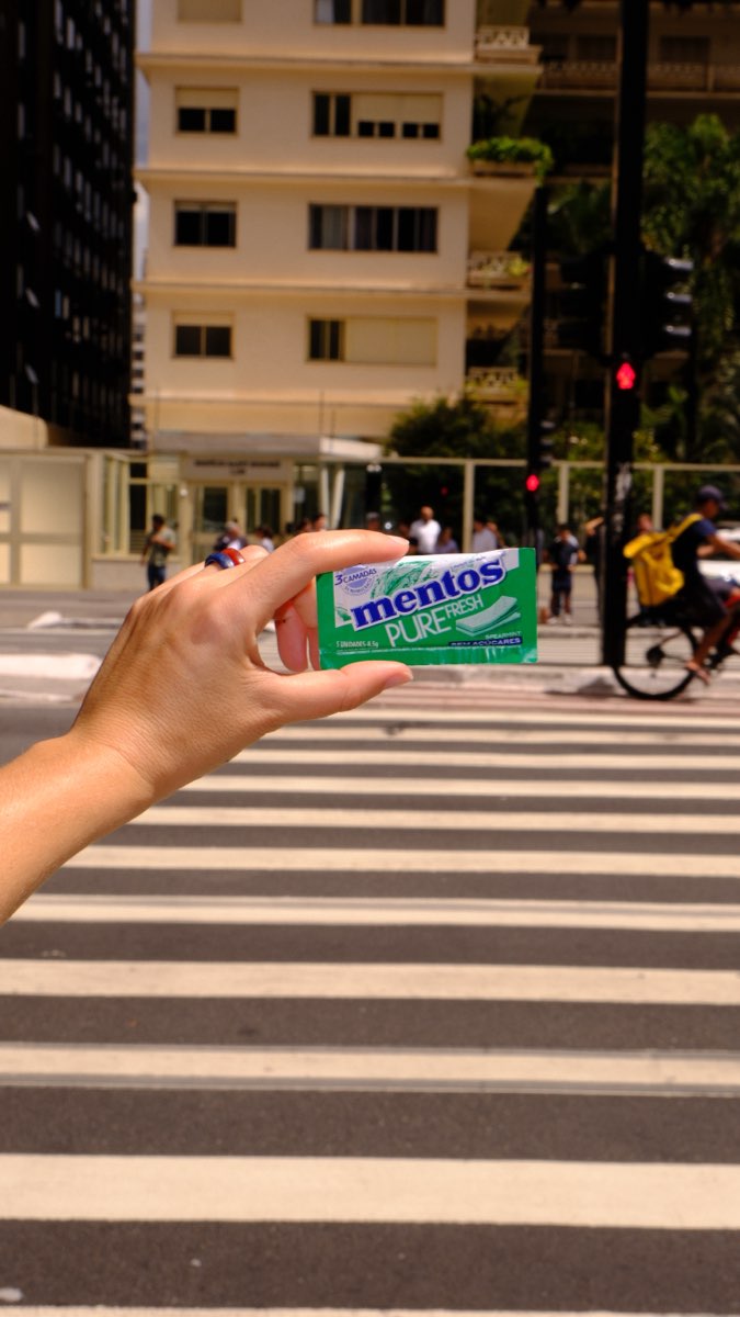 Pacote de Mentos contra a faixa de pedestres da Paulista, com um ciclista passando