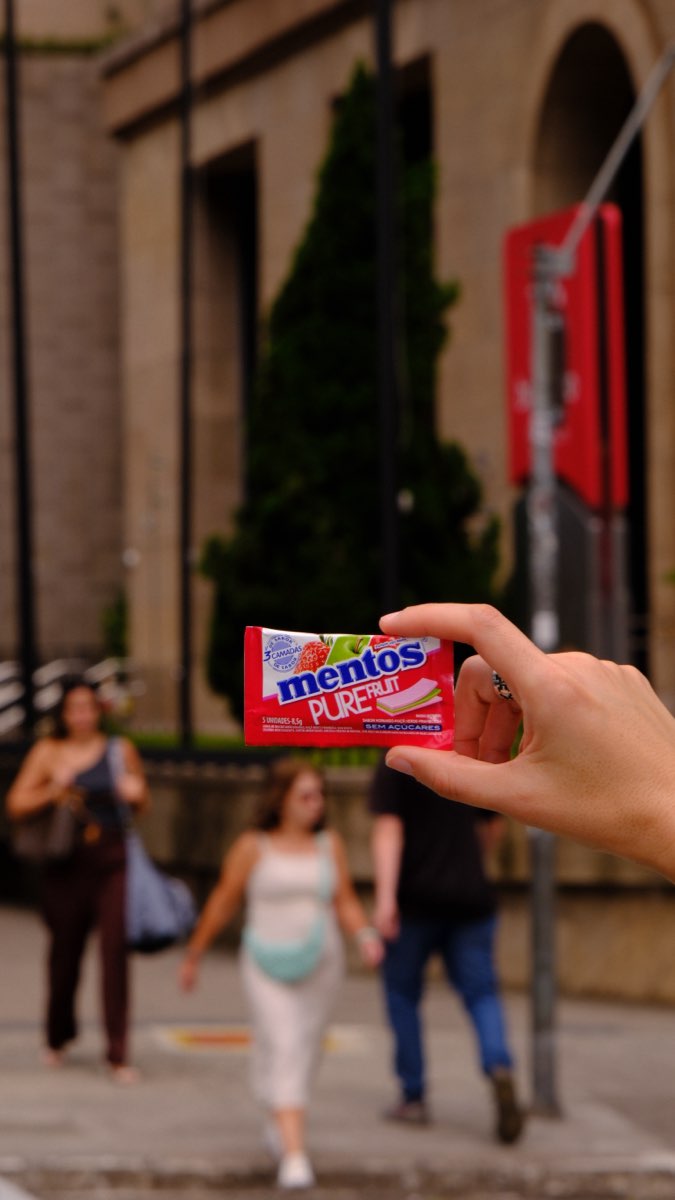 Pacote de Mentos com pessoas caminhando ao fundo, na rua