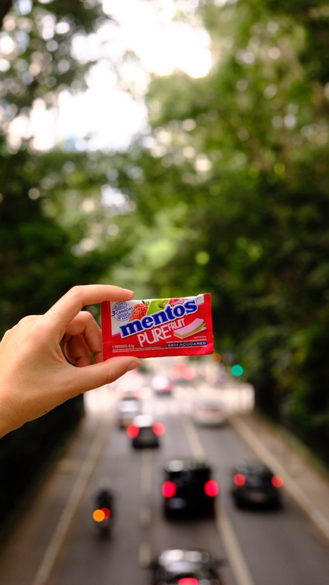 Pacote de Mentos sobre o trânsito da avenida, com o verde fora de foco