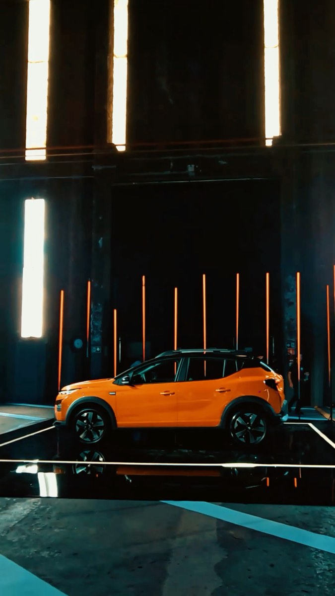O carro laranja no salão escuro, entre as barras de luz